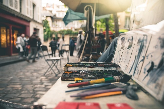 An artist's easel, brushes and drawings set up at Place du Tertre