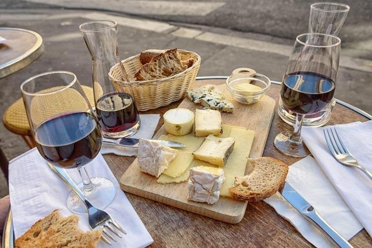 A board of French cheeses and two glasses of wine on a Montmartre food tour