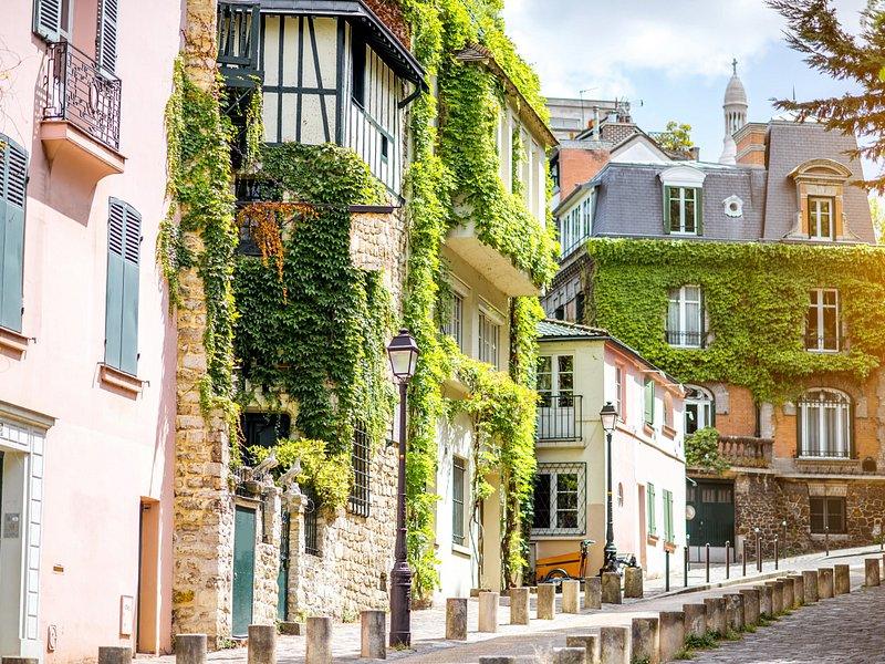 An ivy-covered pink and green corner house on a cobbled Montmartre lane