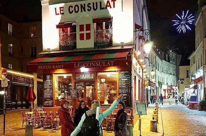 The red frontage of Le Consulat restaurant on a Montmartre corner at night