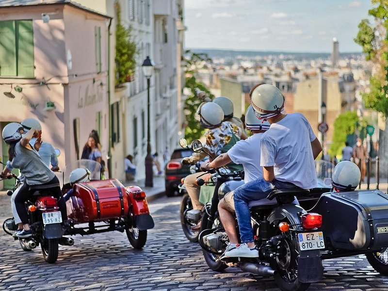 Sidecar motorcycles on a Montmartre lane with the Paris rooftops beyond