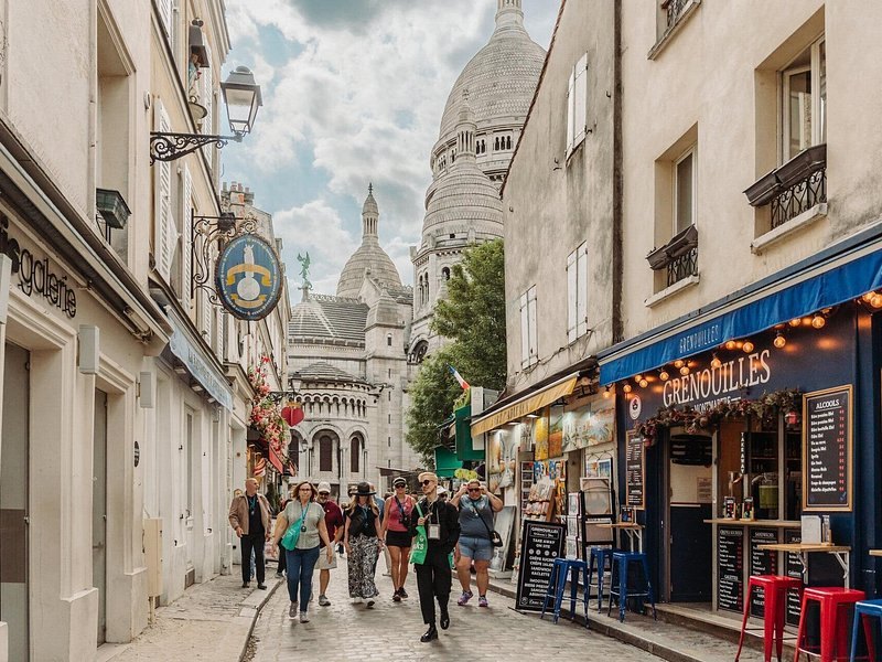 A Montmartre shopping street with the dome of the basilica at the top of it