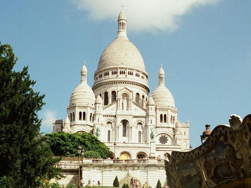 The white domes of the Sacré-Cœur rising behind the Montmartre carousel roof