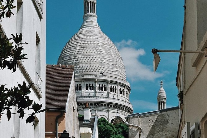 The Sacré-Cœur dome framed by leaves and a street lamp in Montmartre